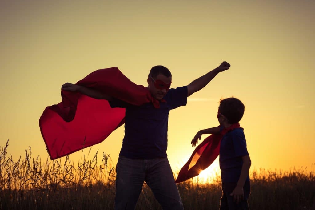 Father and son playing superhero at the sunset time.
