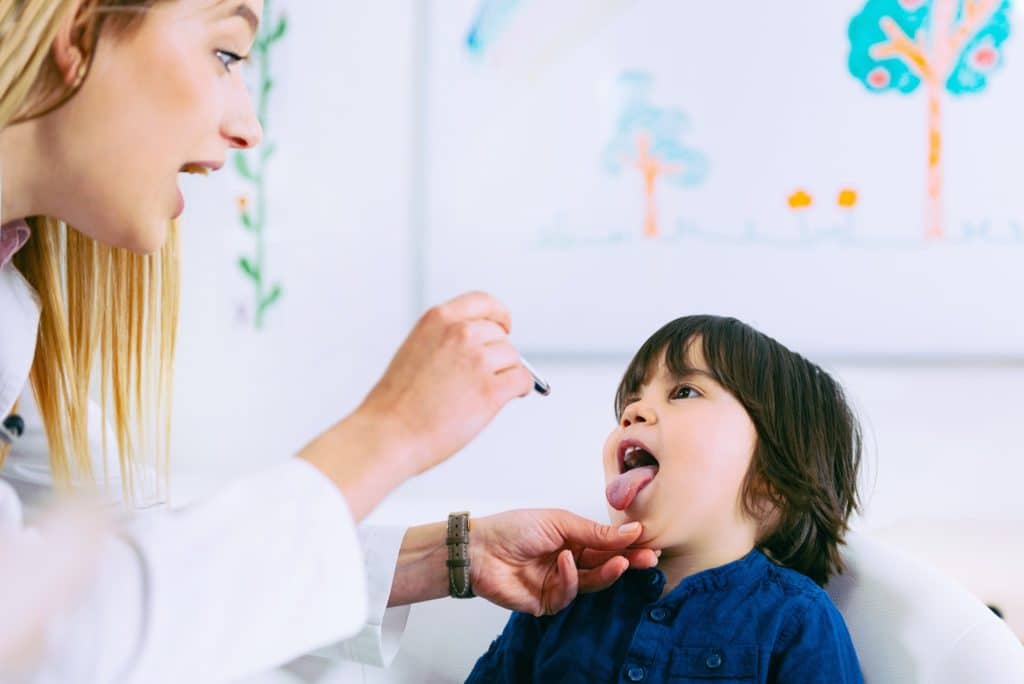 Pediatrician examining little boy’s throat