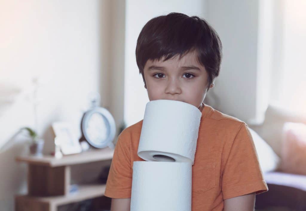 Child carrying a stack of toilet paper, Kid holding toilet roll.