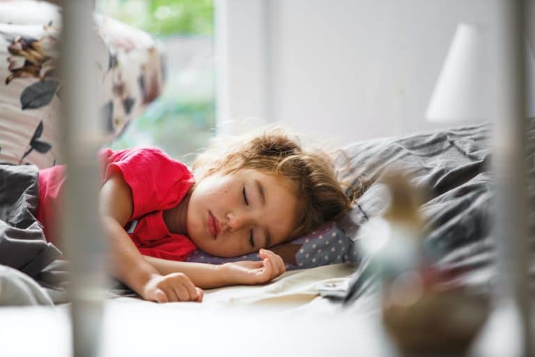 A small child sleeps sweetly in his bed. Healthy sleep of the girl, ventilation
